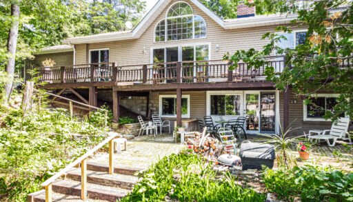 A beige paneled cottage with an upper deck
