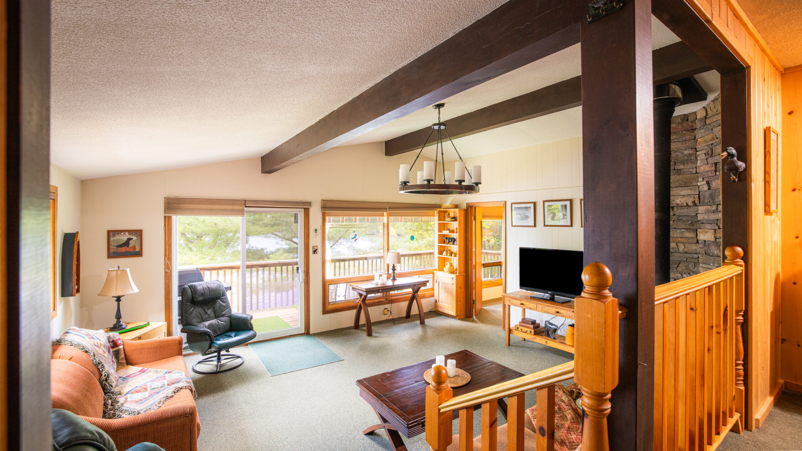 An open-concept living area with wood beams on the ceiling and a green carpet