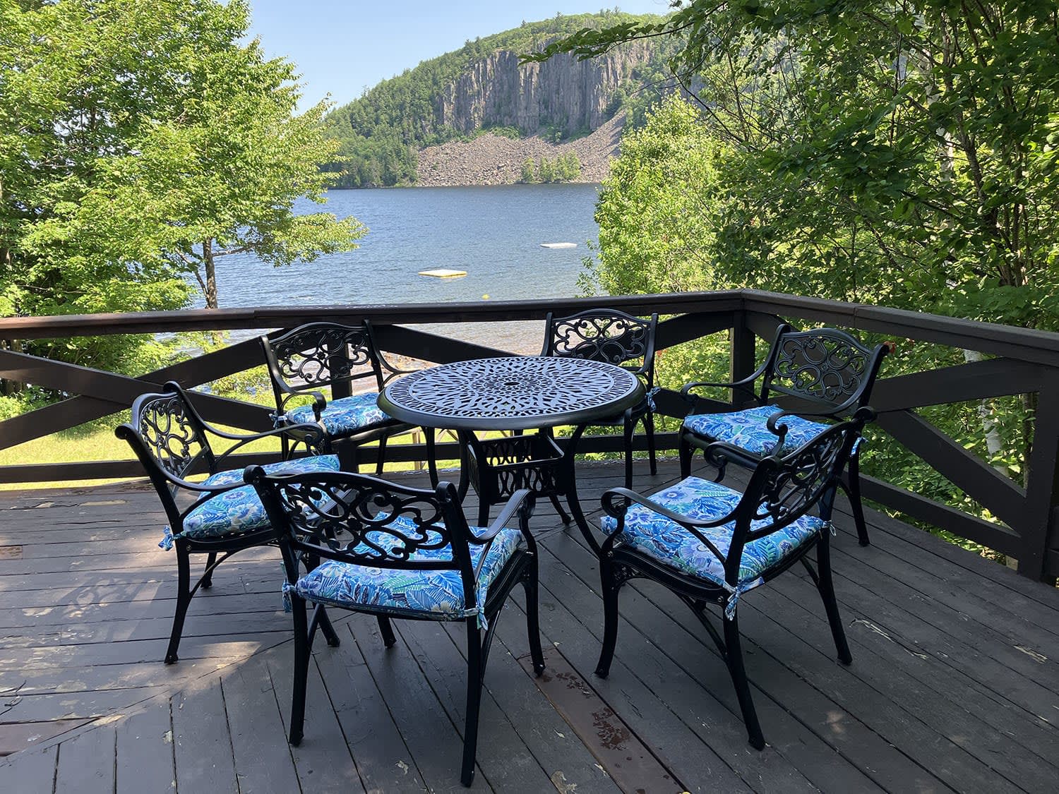 A round metal patio set on a deck overlooking the lake