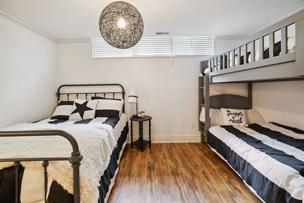 A bed next to bunk beds in a white bedroom