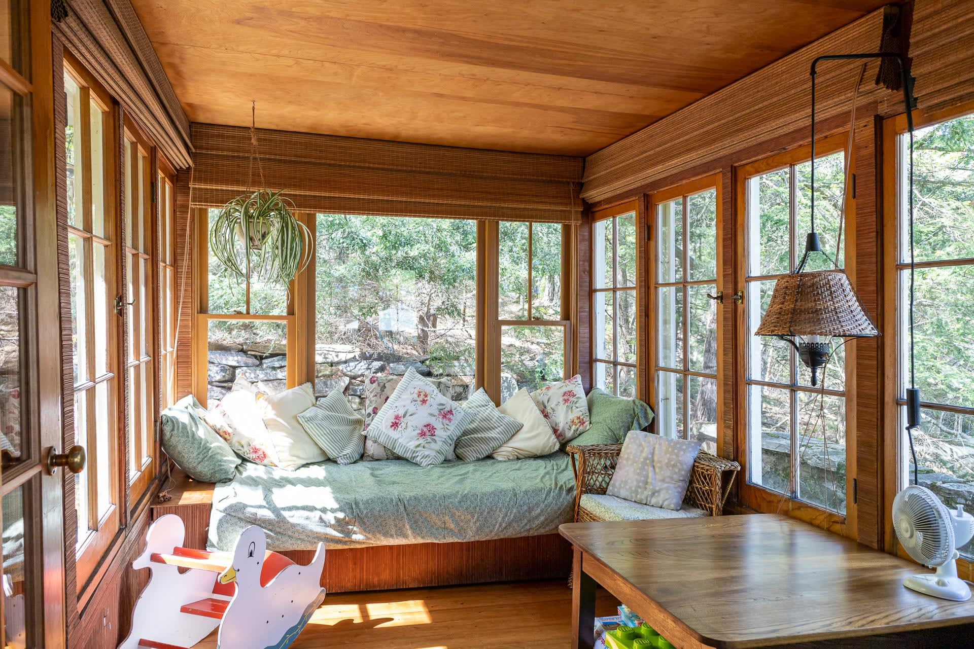 A small green couch in a wood sunroom