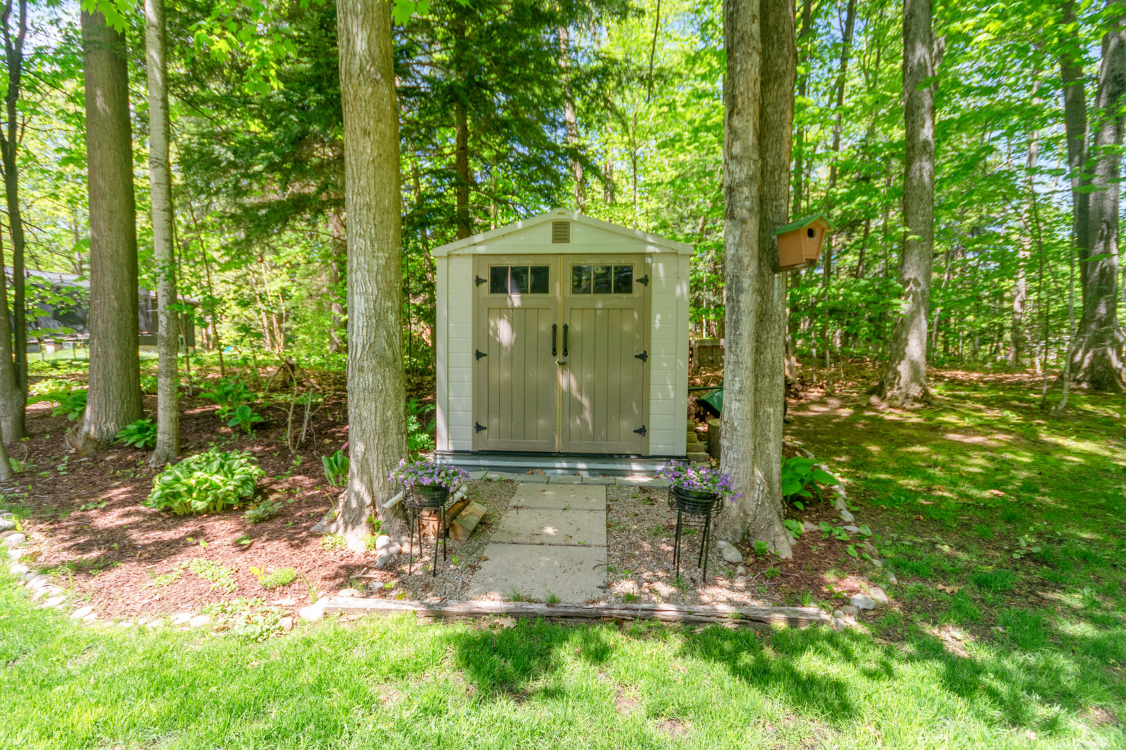 A light green shed on a grassy lawn
