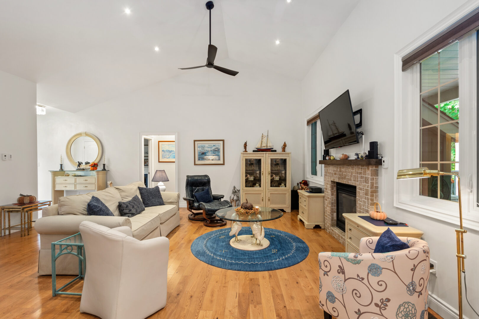 A living room with beige couches face a beige fireplace