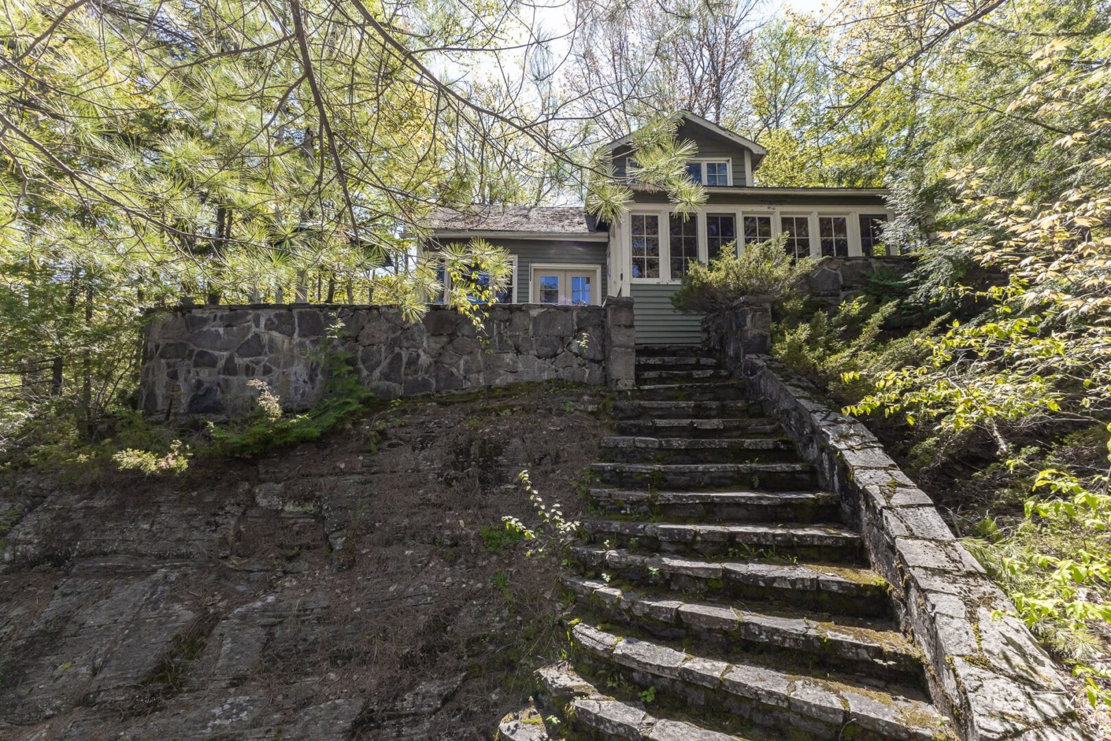 Steps lead up to a cottage tucked in the woods