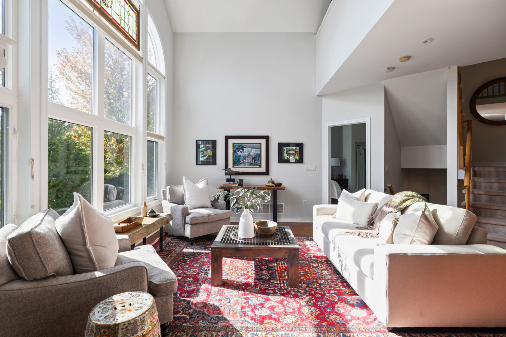 A white living area with white couches and a red rug