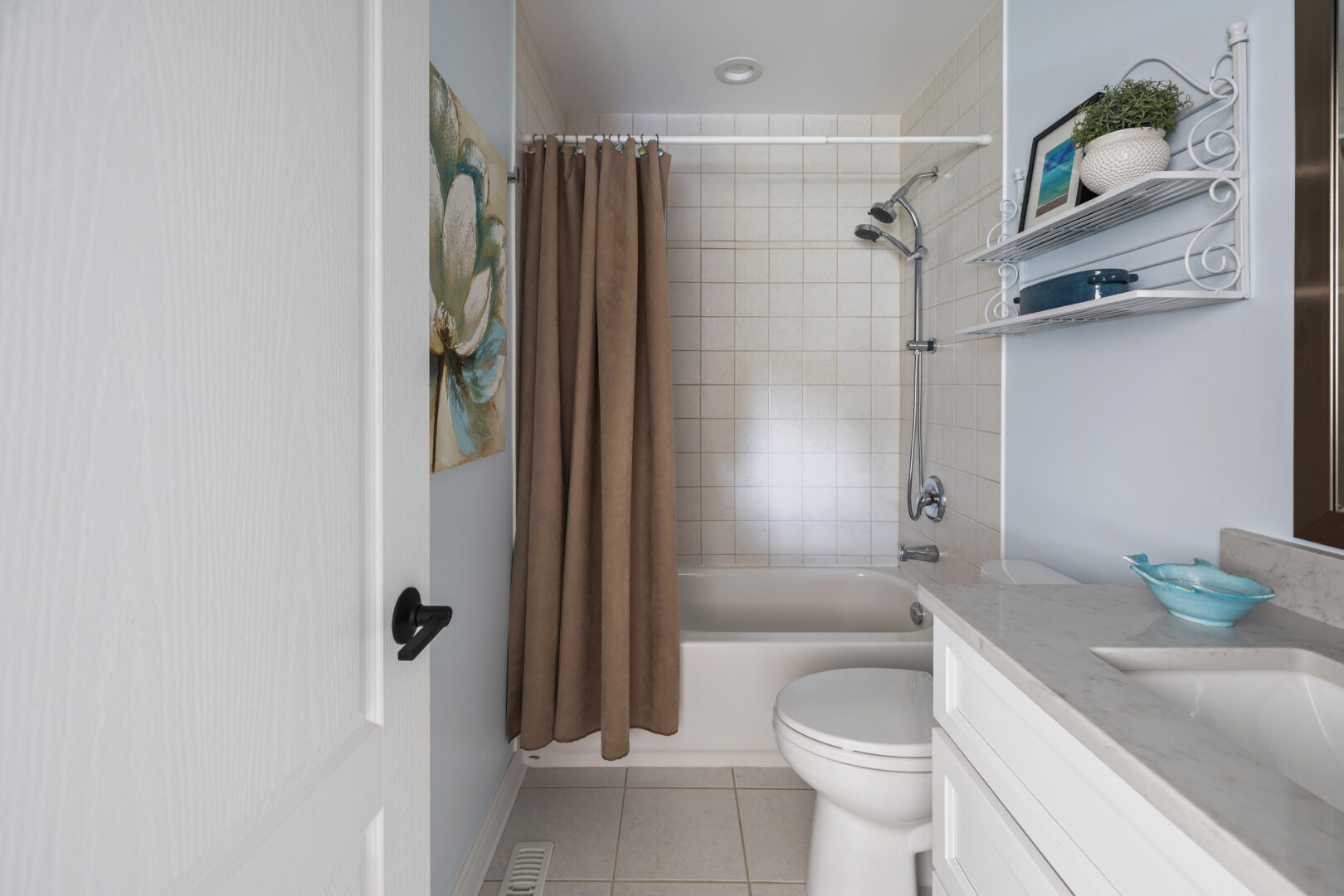 A white bathroom with a light brown shower curtain