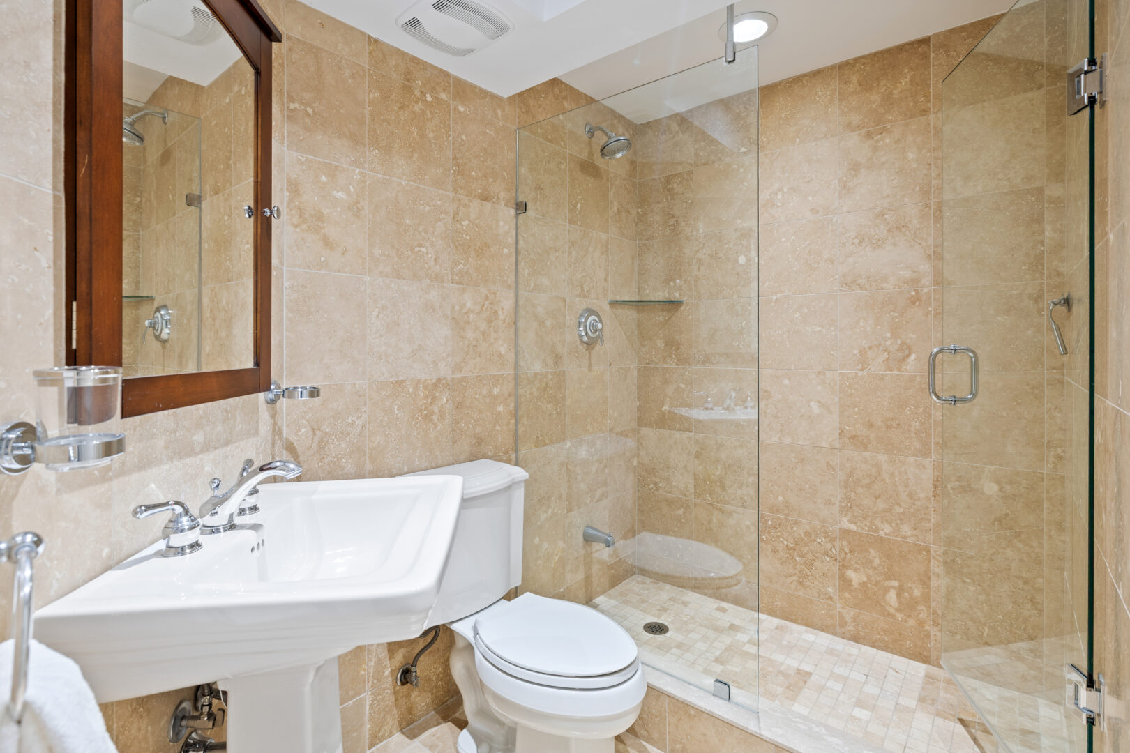 A beige tiled bathroom with a walk-in shower