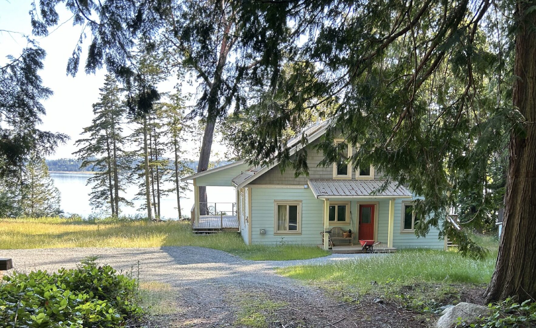 Wooded front entry of west coast-style cottage overlooking the water