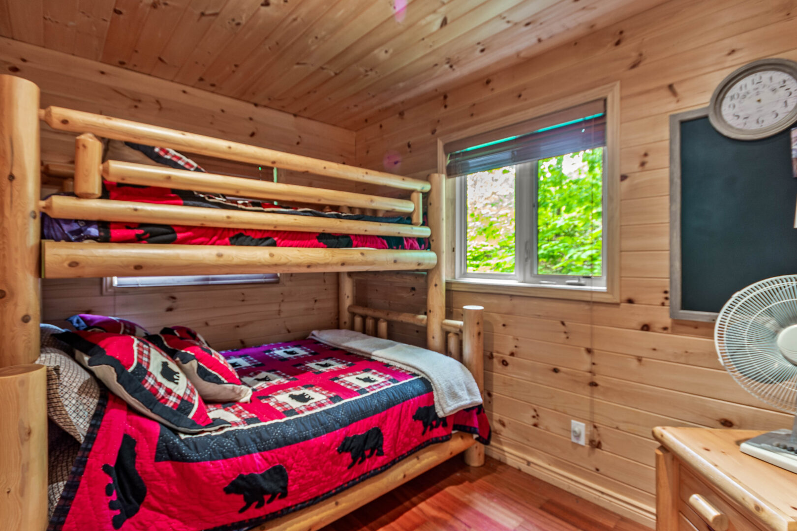 Wood bunk beds with red bedding in a wood paneled room