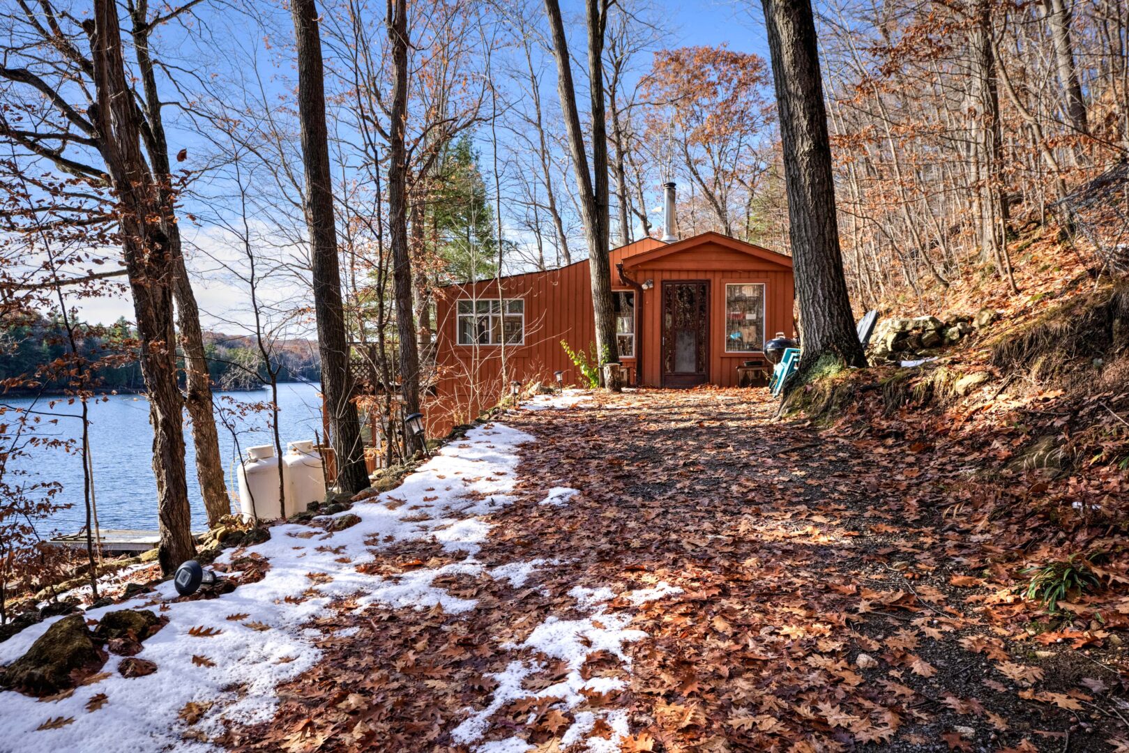 A leafy path to an orange wood cabin