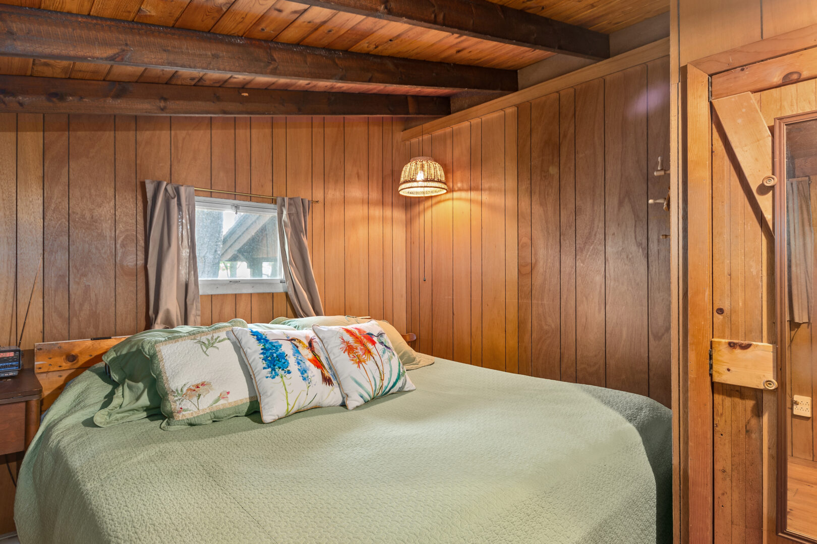 A sage green bed in a wood paneled room