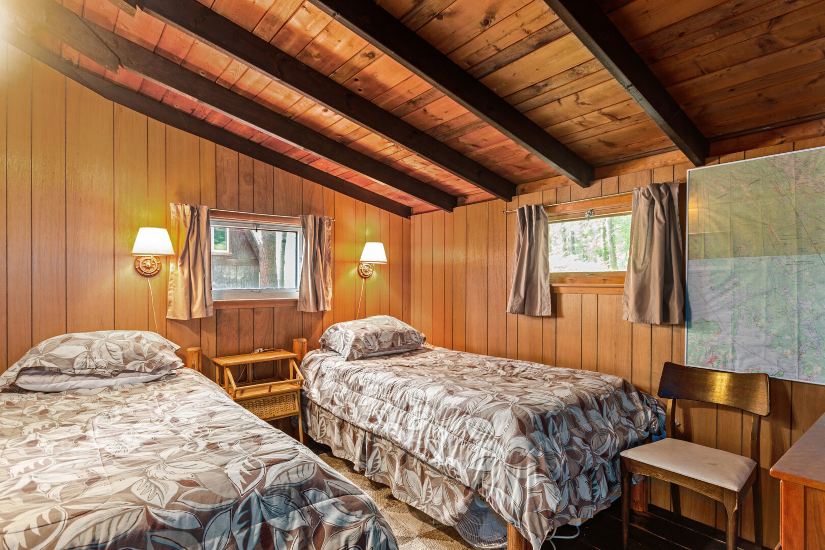 Two twin beds with patterned covers in a wood paneled room