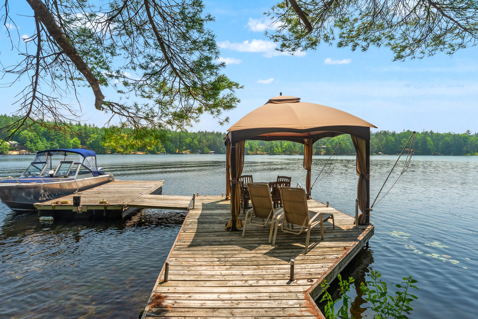 A dock with a pergola and lounge chairs