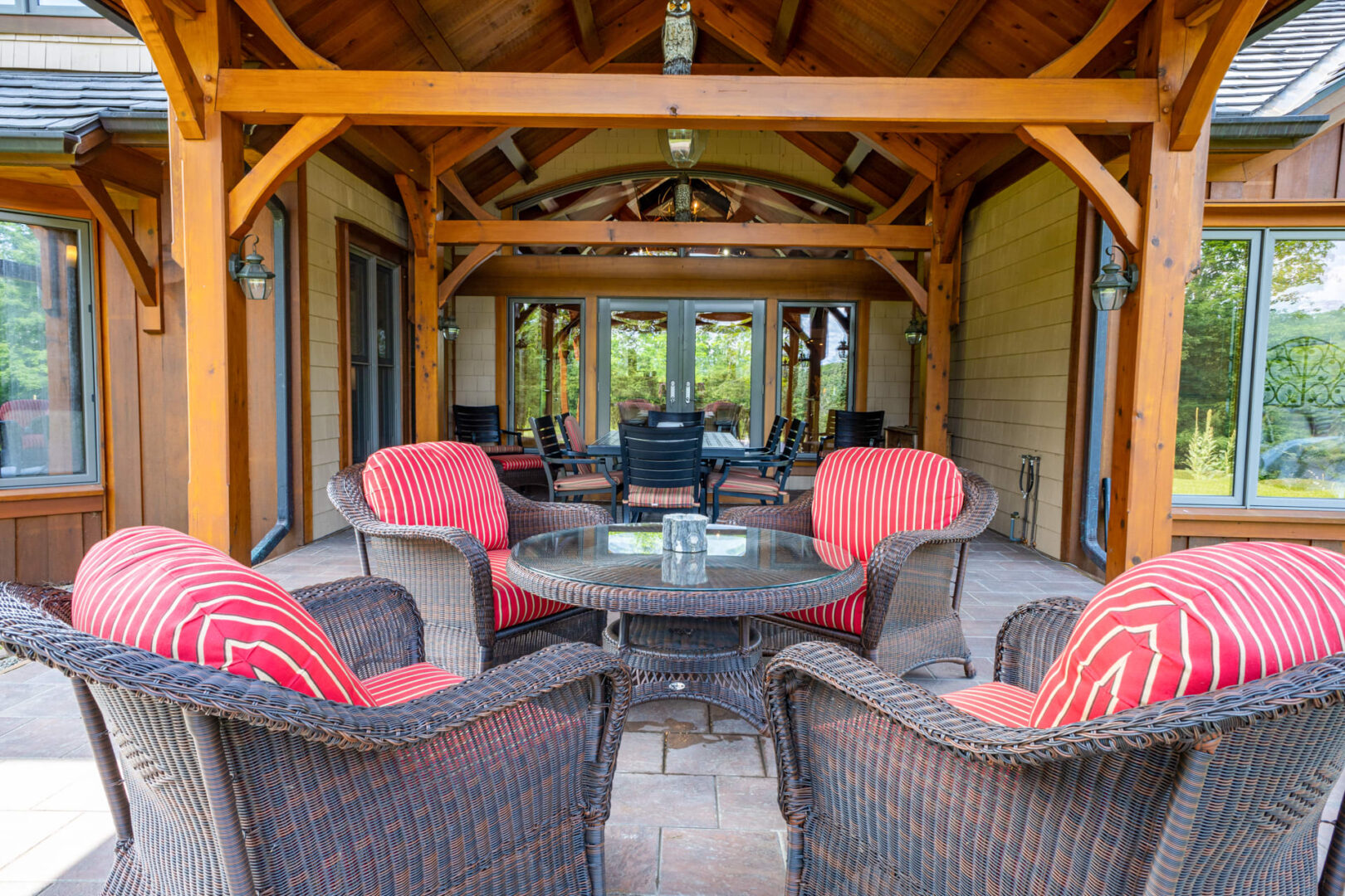 Black patio furniture chairs with red cushions on a patio with wood beams overhead