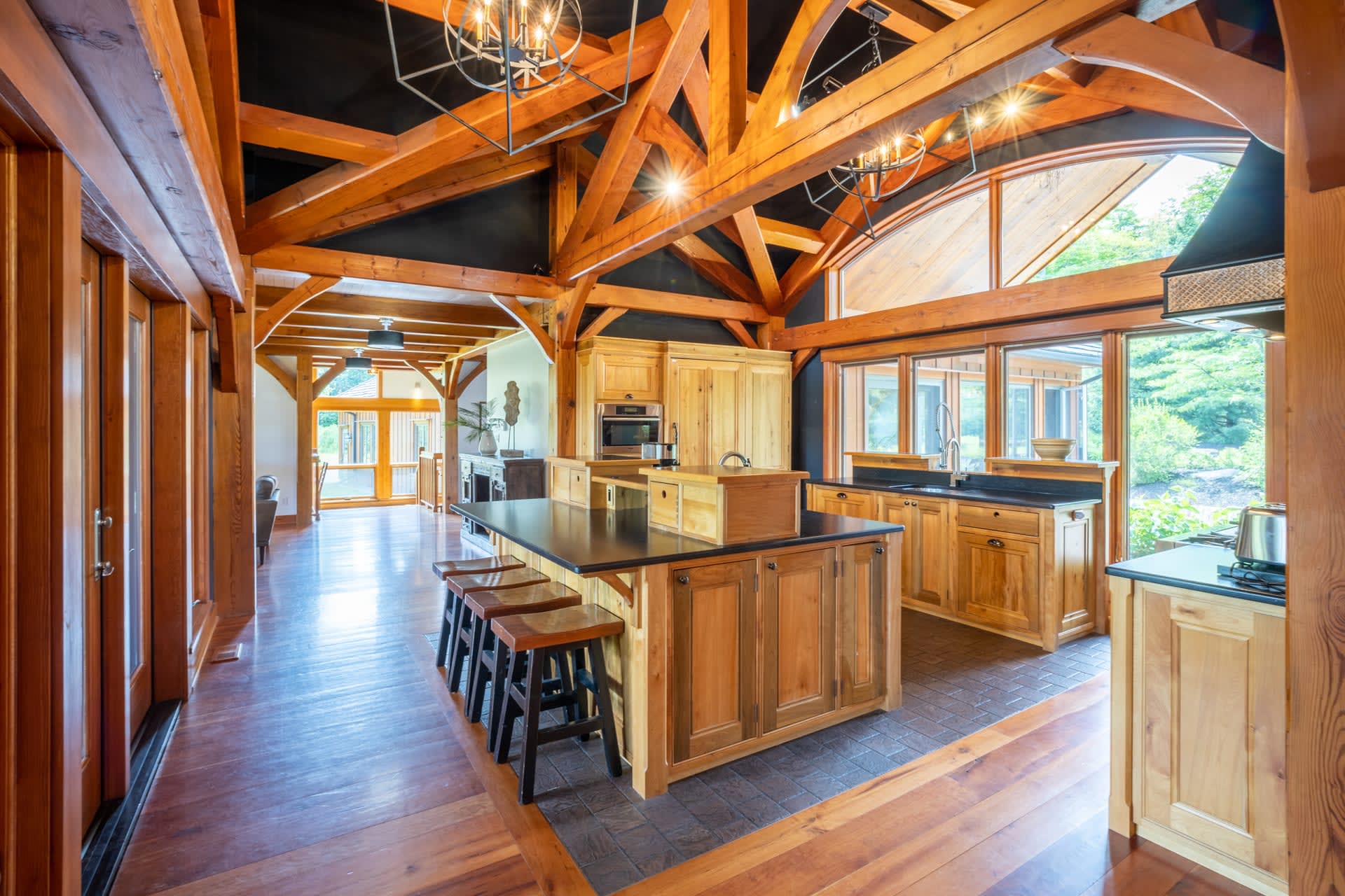 A spacious kitchen with dark wood floors and wood beams above. An oversized island is in the middle