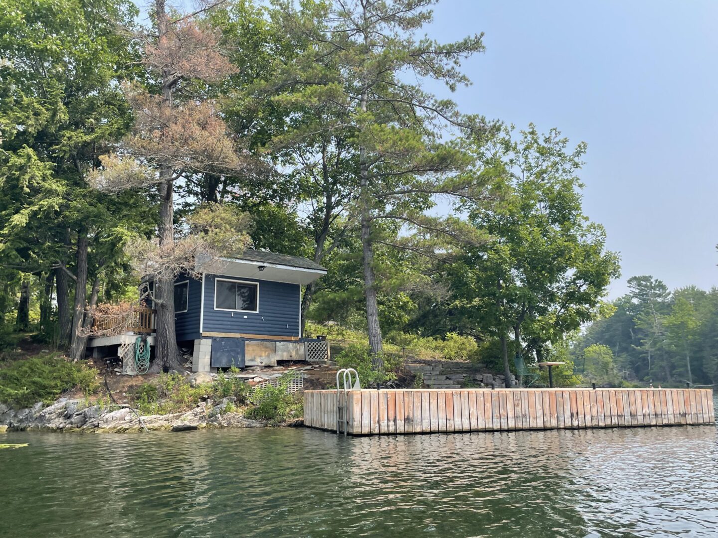 A blue boathouse next to a dock in a forested area