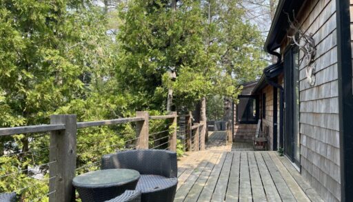 A wood deck with a small sitting area outside a wood cabin