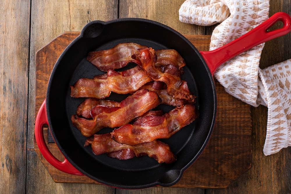 A frying pan full of side bacon resting on a trivet