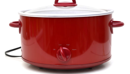 A red slow cooker against a white background